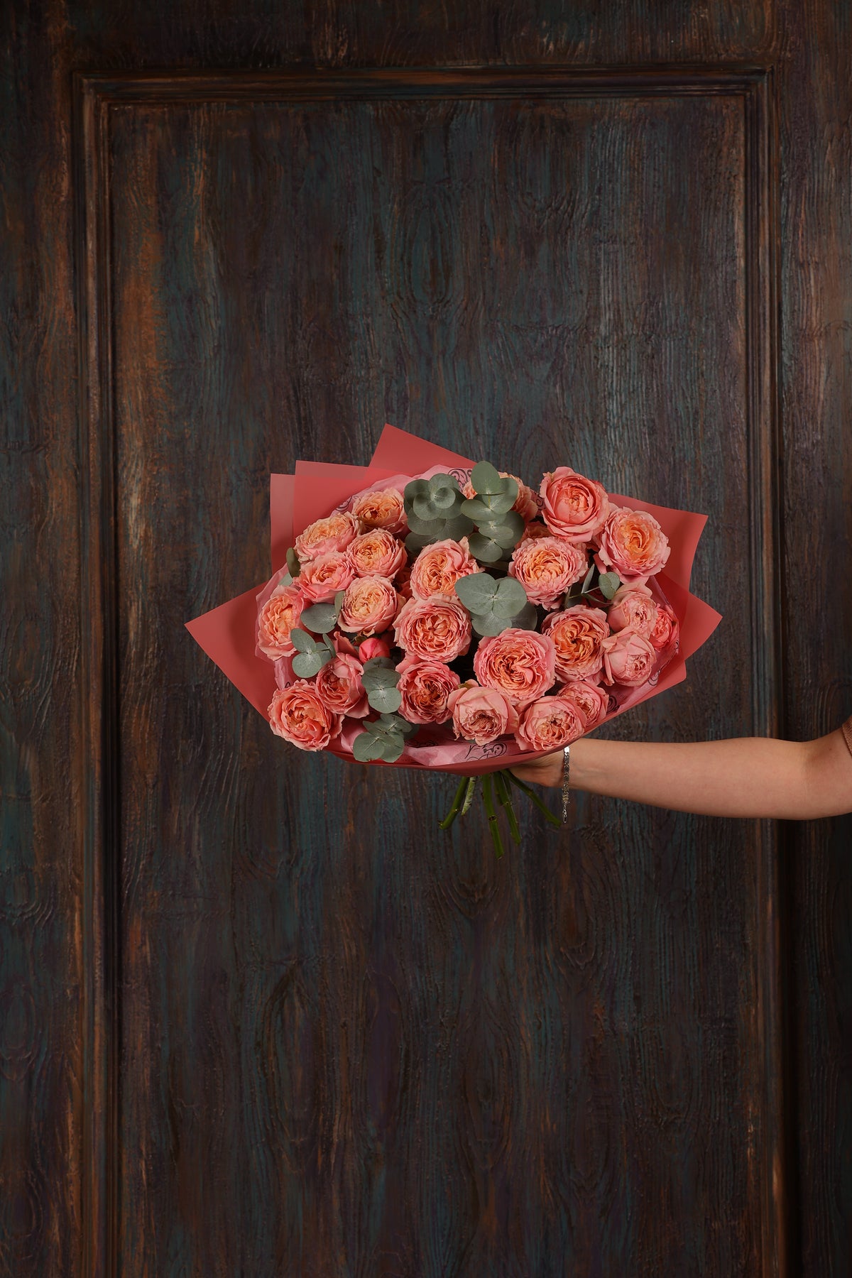 Peach and coral rose bouquet with eucalyptus in rose-toned wrapping